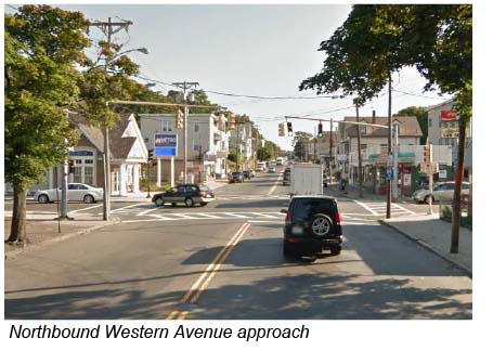 This is a photo taken from the perspective of a driver in the northbound lane of Western Avenue approaching the intersection. The shows the traffic signal at the intersection and some nearby buildings.