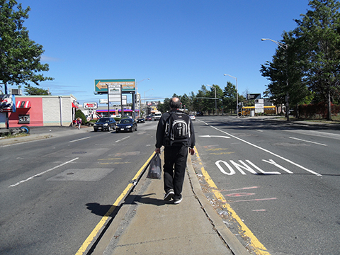 Photo of pedestrian walking on median with three lanes of traffic on either side