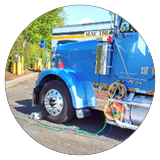 A blue semi truck is hooked up to a charging station.
